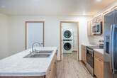 Located at 400 Larkin St in Tomah, Wisconsin, this well-appointed one-bedroom, one-bathroom unit offers a functional and comfortable single-floor layout. The open-concept kitchen and living area serves as the heart of the home, featuring light wood cabinetry, marble-look countertops, a central island with a double-basin sink, and a full suite of stainless steel appliances including a range, over-the-range microwave, and French door refrigerator with ice and water dispenser. Recessed lighting illuminates the kitchen, while the adjacent living area benefits from natural light through vertical-blind windows and is equipped with a wall-mounted air conditioning unit and baseboard heating. Hardwood-style flooring flows consistently throughout the entire unit, adding warmth and cohesion. The spacious bedroom includes a ceiling fan with light, dual closets with wire shelving, a window with vertical blinds, and baseboard heat. The bathroom offers a clean, modern aesthetic with light wood vanity cabinetry, a wide mirror, and hardwood-style flooring. A dedicated laundry room houses a stacked LG washer and dryer unit alongside wire storage shelving, providing exceptional in-unit convenience.
