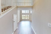 Located at 3435 Pinewalk Dr N in Margate, FL, this two-story home offers three bedrooms and two bathrooms across a well-designed layout spread over two floors. The main level immediately impresses with its dramatic double-height ceilings in the living room, where light hardwood-style flooring runs throughout and large windows with vertical blinds flood the space with natural light. A staircase with white balustrade railings leads to the upper level, adding architectural character to the open entryway. Sliding glass doors in the living area provide seamless access to an outdoor patio with greenery views, enhancing the bright and airy ambiance. The kitchen is well-appointed with white shaker cabinetry, granite-style countertops, stainless steel appliances including a range, microwave, and dishwasher, and light wood flooring. The bedrooms feature plush carpeting and vaulted ceilings with ceiling fans, offering a comfortable retreat. The primary bathroom stands out with a dual-sink vanity topped with granite counters and an elegant arched window that draws in natural light. The second bathroom includes a tub-shower combo with clean white tile and wood-style flooring, maintaining a cohesive, modern aesthetic throughout the home.