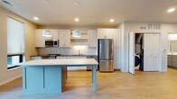 Located at 510 W Washington Ave in Madison, WI, this single-floor unit offers a clean, contemporary design throughout. The open-concept layout connects the kitchen and living areas seamlessly, creating a bright and functional living environment. Light wood-tone flooring runs throughout, lending warmth and visual continuity to the space.

The kitchen is a standout feature, anchored by a distinctive teal island with a crisp white countertop and complemented by pendant lighting overhead. White shaker-style cabinetry lines the walls, paired with a herringbone-patterned tile backsplash that adds texture and style. Stainless steel appliances, including a range, microwave, dishwasher, and refrigerator, provide a modern, polished finish. Open shelving adds additional storage and display options.

A dedicated laundry area with a full-size washer and dryer is conveniently tucked behind bifold doors near the kitchen. The living area is generously sized, with recessed lighting and access to a glass sliding door that brings in natural light and outdoor views.

The bathroom features a white quartz vanity countertop, an undermount sink, brushed nickel hardware, and a framed mirror, delivering a refined and functional design. The bedroom offers a neutral, open canvas with ample space and hardwood-style flooring. A programmable thermostat adds convenience throughout the unit.