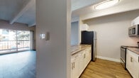 Located at 11100 E Dartmouth Ave in Denver, Colorado, this single-floor residence offers a thoughtfully laid-out living space with a variety of notable features throughout. The living room serves as the centerpiece of the home, showcasing dark wood-style flooring, a textured ceiling, and a classic brick fireplace that adds warmth and character. A pass-through counter connects the living area to the kitchen, which is equipped with stainless steel appliances including a refrigerator, electric range, and over-the-range microwave, complemented by white cabinetry and stone-look countertops. Light wood-style flooring runs through the kitchen for a clean, cohesive finish. The bedrooms feature plush carpeting and exposed beam ceilings that lend an architectural charm to the space. One bedroom includes a walk-in closet and sliding glass doors that open to a private balcony with outdoor views, filling the room with natural light. A second bedroom displays a striking painted brick accent wall and a large window with garden views. The bathrooms are finished with wood-style flooring, white cabinetry, and stone-look countertops, with one featuring a tiled tub-shower combination. Throughout the residence, neutral tones and consistent finishes create a clean, comfortable atmosphere.