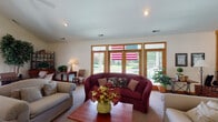 Located at 6755 Brandon Village Way in Canal Winchester, Ohio, this single-floor home offers a comfortable and welcoming layout designed for easy living. The standout feature of the home is the spacious living room, which is bathed in natural light streaming through a generous bank of large windows and glass doors framed in warm wood trim. These expansive windows provide picturesque views of the lush outdoor surroundings, including a well-maintained yard and greenery beyond a white railing deck or patio. The living room features neutral carpeting, recessed lighting in the smooth ceiling, and ample space for relaxed seating arrangements. The warm wood accents on the window and door frames lend a classic, inviting character to the room. Additional rooms in the home, while more dimly captured, include spaces with windowed walls fitted with horizontal blinds, offering privacy alongside natural light. The overall ambiance of the home is cozy and traditional, with a layout that emphasizes comfort and practicality. The single-floor design ensures convenient accessibility throughout, making this Canal Winchester property a well-rounded residential space suited for a variety of lifestyles.