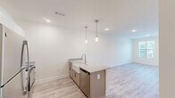 Located on Dellridge Place in Chattanooga, TN, this thoughtfully designed 2-bedroom, 2-bathroom single-story home offers a clean, modern aesthetic throughout. The open-concept kitchen and living area serves as the heart of the home, anchored by a striking center island with granite countertops and a farmhouse-style sink illuminated by stylish pendant lighting. White shaker cabinets, two-tone lower cabinetry in natural wood tones, and stainless steel appliances — including a refrigerator, range, and microwave — complete the well-appointed kitchen. Light wood-look flooring flows throughout the main living areas, enhancing the bright, airy feel created by large windows that invite ample natural light. The spacious primary bedroom features plush carpet, a ceiling fan, and direct access to an en-suite bathroom and dedicated closet. The second bedroom is equally well-lit, with its own ceiling fan and window views. Both bathrooms are finished with wood-tone vanities and granite countertops, with one featuring a tub-shower combo and a natural light window. Additional conveniences include three closets, a laundry area, and a hallway connecting the private quarters. The overall ambiance is fresh, neutral, and move-in ready.
