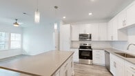 Located at 1911 Waterway Cir in Middleburg, FL, this single-floor, 2-bedroom, 2-bathroom home offers a clean, contemporary design throughout. The open-concept kitchen is a standout feature, showcasing white shaker cabinetry, stainless steel appliances including a range, microwave, dishwasher, and refrigerator, neutral quartz-style countertops, a subway tile backsplash, and a central island with pendant lighting overhead. Light wood-look flooring runs through the main living areas, enhancing the bright and airy feel. The living room benefits from natural light and includes a ceiling fan. The spacious primary bedroom features plush carpeting, multiple windows with blinds, and access to a generous walk-in closet outfitted with wire shelving systems. The second bedroom is similarly carpeted and naturally lit. Both bathrooms are finished with white cabinetry, neutral countertops, wood-framed mirrors, and wood-look tile flooring; one bathroom includes a tub-shower combination. A stacked washer and dryer unit is conveniently integrated into the layout. Two closets provide ample storage throughout the home, completing this well-organized and modern living space.
