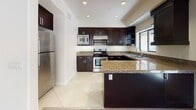 This single-floor residence is thoughtfully designed with a consistent aesthetic throughout. The entry foyer features neutral-toned walls and large-format tile flooring, establishing a clean, welcoming introduction to the space. A hallway with recessed lighting and a ceiling-mounted HVAC vent connects the main living areas efficiently.

The kitchen is a standout feature, equipped with rich dark espresso cabinetry, granite countertops, and stainless steel appliances including a refrigerator, gas range, and built-in microwave. A peninsula provides additional prep and seating space, while a window above the sink introduces natural light. Tile flooring continues throughout the kitchen.

The bedrooms are carpeted and generously proportioned, each featuring windows that allow natural light. One bedroom connects directly to a bathroom and a walk-in closet, providing a practical en-suite layout.

The bathrooms feature tile flooring, dark vanity cabinetry with granite countertops, and framed mirrors. One bathroom includes a soaking tub with subway tile surround and a separate glass-enclosed shower, while a second bathroom offers a tub-shower combination.