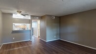 Located at 8550 E Speedway Blvd in Tucson, Arizona, this single-story unit offers a well-organized and functional layout throughout. The living area is finished with rich, dark hardwood-style flooring that extends from the entry through the main living space, complemented by neutral gray-toned walls and a textured ceiling. A ceiling fan adds practicality to the room, while a window at the front of the unit allows natural light to filter in alongside views of the exterior landscaping.

The galley-style kitchen is efficiently designed with white cabinetry lining both sides, light wood-look flooring, and a suite of stainless steel appliances including a refrigerator, range, and dishwasher. A built-in breakfast bar provides a convenient pass-through to the living area.

The bedrooms feature plush carpeting, textured walls, and ample closet space, with one room also accommodating a stacked in-unit washer and dryer. The bathroom is cleanly appointed with white cabinetry, a single-basin vanity with light countertops, a full tub and shower combination, and wood-look flooring. Consistent neutral tones and textured wall finishes tie the space together throughout, creating a cohesive and move-in-ready environment.