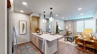 Located at 2080 FM 1102 in New Braunfels, Texas, this thoughtfully designed one-bedroom, one-bathroom residence offers a cohesive blend of modern style and functional living across a single floor. The open-concept kitchen and living area serves as the heart of the home, where a sleek galley-style kitchen impresses with warm wood cabinetry, quartz countertops featuring subtle veining, a stainless steel sink with a matte black faucet, and stainless steel appliances. Globe pendant lights hang above a generous kitchen island with bar seating, making it ideal for casual dining or entertaining. The adjoining living room is bright and welcoming, with large windows that invite natural light and recessed lighting overhead. Hardwood-style flooring flows seamlessly throughout the space, adding warmth and visual continuity. The spacious bedroom offers expansive windows with views of the surrounding landscape, a ceiling fan, and ample room for a comfortable retreat. The bathroom features a long wood-tone vanity with an LED-lit mirror, white quartz countertops, and a glass-enclosed walk-in shower with marble-style tile. A dedicated laundry area with washer and dryer and a well-proportioned closet round out the practical amenities of this refined residence.