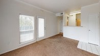 This single-floor residential unit offers a clean, functional layout with a neutral color palette throughout. The living area is welcoming and filled with natural light from large windows dressed with blinds, and features warm, wall-to-wall carpeting that extends through the main gathering space. A glass-paneled exterior door provides access to the outdoors and adds to the sense of openness. Crown molding accents the ceiling, adding a subtle architectural detail to the room.

The entryway transitions from tiled flooring into the carpeted living area, creating a natural delineation of space. Adjacent to the living room, the kitchen is efficiently designed with white cabinetry offering ample storage, warm-toned laminate countertops, a stainless steel sink, and white appliances including an electric range and built-in microwave. Tile flooring in the kitchen is practical and easy to maintain.

The bedroom is generously sized, carpeted, and bathed in soft, even light, offering a comfortable and restful environment. The bathroom features a full-size soaking tub with an overhead shower, finished with clean white tile and a tasteful taupe accent border, chrome fixtures, and crisp white cabinetry. Throughout the unit, the consistent use of light tones and neutral finishes creates a cohesive, airy ambiance.