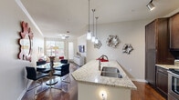 Located at 11400 Edgemere Blvd in El Paso, TX, this well-appointed one-bedroom, one-bathroom residence offers a thoughtfully designed single-level layout. The open-concept living, dining, and kitchen area forms the heart of the home, anchored by rich hardwood-style flooring that flows throughout. The kitchen is a standout feature, showcasing dark espresso cabinetry reaching to the ceiling, granite countertops, a large peninsula with an undermount sink, stainless steel appliances including a range, microwave, and refrigerator, and stylish pendant lighting above. The combined dining and living area is bright and welcoming, with multiple windows dressed in plantation blinds that invite natural light and views of the outdoors. Crown molding and a ceiling fan add refined detail to the living space. The bedroom is a comfortable retreat featuring plush carpeting, a generous window, and two closets for ample storage. The bathroom continues the granite and dark cabinetry motif, complemented by hardwood-style flooring and a tiled tub-shower combination. A dedicated in-unit laundry area with overhead shelving adds everyday convenience. An entrance hallway and an arched architectural detail between the kitchen and hallway lend a classic touch to the overall design.