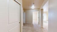 Located in the Harbour Landing community of Regina, Saskatchewan, this one-bedroom, one-bathroom unit offers a practical and efficient layout designed for comfortable everyday living. The kitchen is a standout feature, finished with rich dark-toned cabinetry, light countertops, and durable tile flooring. It is equipped with a full suite of black appliances, including a refrigerator, electric range, and over-the-range microwave, along with a peninsula that provides additional workspace and a natural transition into the living area. Soft, neutral-toned carpet flows throughout the living space, hallway, and bedroom, creating a warm and cohesive feel. The bedroom is a well-sized retreat featuring a sliding closet door and clean, cream-toned walls, offering a calm and understated atmosphere. The hallway connects all areas of the unit efficiently and provides access to an in-suite washer and dryer, adding significant day-to-day convenience. The bathroom includes a full-sized soaker tub and shower combination with clean white surround, a toilet, and chrome fixtures. Throughout the unit, the neutral color palette, flush-mount lighting, and consistent finishes contribute to a clean, move-in-ready aesthetic.