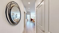 Located at 17501 Dallas Parkway in Dallas, TX, this well-appointed one-bedroom, one-bathroom residence offers a thoughtfully designed single-floor layout with a clean, contemporary aesthetic throughout. A bright entryway hallway with recessed lighting and light wood-style flooring leads into the open-concept kitchen and living area. The kitchen is a standout feature, boasting white shaker cabinetry, a subway tile backsplash, stainless steel appliances including a French door refrigerator, and a spacious waterfall island with bar seating illuminated by industrial-style pendant lights. The adjoining living room is bathed in natural light from large floor-to-ceiling windows and features a ceiling fan overhead, creating an airy, comfortable atmosphere. The bedroom continues the light, neutral palette with plush carpeting, a ceiling fan, and expansive windows that bring in generous outdoor views. A dedicated closet with full-width hanging storage connects directly to the bedroom. The bathroom is finished in crisp white tones with wood-style flooring, a wide vanity with under-mount sink, backlit mirror, and a tiled tub-shower combination. Recessed lighting throughout the unit ensures a bright and welcoming ambiance in every room.