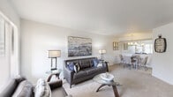 This well-appointed one-bedroom, one-bathroom residence in Sterling Heights, Michigan offers a thoughtfully designed single-floor layout that maximizes functionality and comfort. The combined living and dining area forms the heart of the home, featuring neutral-toned carpet, bright white walls, and large windows that invite natural light throughout the space. The living room provides generous room for seating and entertainment, while the adjacent dining area is defined by a stylish pendant chandelier and a half-wall pass-through that connects visually to the kitchen, enhancing the open feel of the space. The galley-style kitchen is efficiently designed with white cabinetry, granite-toned countertops, stainless steel appliances including a refrigerator and microwave, and tile flooring. The spacious primary bedroom features plush carpeting, clean white walls, and direct access to a closet. Two additional closets throughout the unit offer exceptional storage capacity. The combined bathroom and laundry room includes a full tub-shower combo, a vanity with granite-style countertops, tile flooring, and a large mirror. With three closets and a practical, cohesive design, this residence delivers comfort and convenience in a quiet Sterling Heights location.