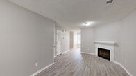 Located at 3841 SW Windsong Dr in Lee's Summit, Missouri, this two-story home offers a clean, neutral aesthetic with a well-considered layout across both levels. The main living area is an open, airy space finished with light-toned vinyl plank flooring and a textured ceiling. A classic fireplace with a white mantel serves as a natural focal point, adding warmth and character to the room. A louvered-door closet and a window providing natural light round out this inviting common space. The kitchen is outfitted with white cabinetry, light countertops, and a full suite of stainless steel appliances including a refrigerator, range, microwave, and dishwasher. A skylight brightens the kitchen, while a door with adjacent windows offers an abundance of natural light and exterior access. The bedrooms are carpeted for comfort and feature ceiling fans, windows with blinds, and generous closet space — including what appears to be a walk-in closet with built-in shelving in one room. Bathrooms are visible in the dollhouse view, reflecting the same clean, neutral palette found throughout. Consistent gray-toned walls, white trim, and textured ceilings create a cohesive, move-in-ready atmosphere from top to bottom.
