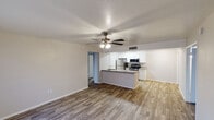 Located at 144 N Lesueur in Mesa, Arizona, this single-story home presents a clean, updated interior with a cohesive design throughout. The open-concept living and kitchen area is a central highlight, featuring wood-style plank flooring, neutral-toned walls, and a ceiling fan with light fixture that enhances airflow and comfort. A peninsula counter with granite-style countertops separates the living space from the kitchen, which is equipped with stainless steel appliances including a refrigerator, range, and microwave, complemented by white shaker-style cabinetry and matching countertops.

The living area includes a sliding glass door fitted with vertical blinds, allowing natural light to filter in while providing access to an outdoor patio. Additional rooms feature the same wood-style flooring, ceiling fans, and windows with blinds that invite natural light. One bedroom also includes a sliding glass door opening to the exterior.

The bathrooms maintain a consistent aesthetic with white cabinetry, granite-style countertops, undermount sinks, and full tub-shower combinations set against light, neutral walls and wood-style flooring. The overall atmosphere of the home is bright, functional, and move-in ready, with updated finishes that lend a modern, well-maintained feel throughout.