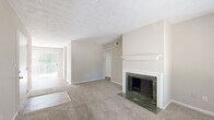 This single-floor residence offers a well-organized layout combining comfortable living spaces with practical design. The living room serves as a central gathering area, highlighted by a standout fireplace framed in green marble with a classic white mantel surround—an elegant focal point set against neutral-toned walls and plush carpeting. Natural light enters through a sliding glass door, adding brightness to the open feel of the space.

The kitchen features white shaker-style cabinetry, a white subway tile backsplash, gray countertops, and wood-look vinyl flooring. Black appliances, including a range, dishwasher, and refrigerator, provide a bold contrast to the clean white finishes. A window above the sink allows natural light to filter in.

The bedrooms are carpeted and neutrally painted, each equipped with ceiling fans for ventilation. The primary bedroom includes a closet and direct access to a bathroom. Additional bedrooms offer windows with natural views and ample floor space. The bathroom is outfitted with a single-sink vanity featuring dark countertops, a tiled tub-shower combination, and wood-look flooring. Throughout, textured ceilings and clean white trim add consistent architectural detail.