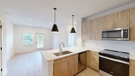 Located at 1095 Union St in Spartanburg, SC, this thoughtfully designed 2-bedroom, 2-bathroom residence offers a clean, modern aesthetic across a single floor. The open-concept living area seamlessly connects the kitchen, dining, and living spaces, creating a bright and airy atmosphere enhanced by recessed lighting and natural light from multiple windows.

The kitchen serves as a central hub, featuring a large island with a quartz countertop, undermount stainless steel sink, and two striking black pendant lights overhead. Light wood-toned cabinetry, a herringbone tile backsplash, and a full suite of stainless steel appliances — including a French door refrigerator, range, microwave, and dishwasher — complete the space. A pantry provides additional storage.

Both bedrooms are well-proportioned and finished with light hardwood flooring, ceiling fans, and windows overlooking greenery outside. The primary bedroom connects to a spacious en-suite bathroom featuring a wide vanity with wood cabinetry, quartz countertop, a glass-enclosed shower, and large-format tile flooring. A generously sized walk-in closet with wire shelving adjoins the primary bath. The second bathroom mirrors the same contemporary design. Three closets total ensure ample storage throughout the residence.