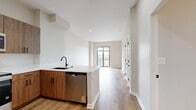 This 570 square foot apartment in Delancey at Shirlington Village offers a thoughtful layout maximizing space and functionality. The open-concept living area seamlessly integrates the kitchen and living room, creating a spacious feel. The modern kitchen boasts wood-grain cabinetry, stainless steel appliances, and a white tile backsplash, complemented by a convenient breakfast bar.

The 130 square foot bedroom provides a comfortable retreat with large windows allowing natural light to flood the space. The bathroom features a sleek design with a wood vanity, white countertop, and a shower/tub combination with white tiling.

Throughout the apartment, warm wood-look flooring adds a touch of elegance and continuity. Large windows in both the living area and bedroom offer views of the surrounding area and fill the space with natural light. The neutral color palette of whites and light grays creates a fresh, modern ambiance.

Storage is thoughtfully incorporated with multiple closets, including those in the entrance area. The apartment's single-floor layout ensures easy accessibility and efficient use of space. This well-designed unit in Delancey at Shirlington Village combines style and functionality, perfect for those seeking a contemporary urban living experience.