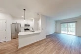 Located at 1061 Dryden Rd in Ithaca, NY, this well-appointed two-story home offers three bedrooms, two bathrooms, and a thoughtfully designed layout across two levels. The main living floor is expansive, hosting a seamlessly connected dining room, kitchen, and living room that together create a bright, open-concept gathering space. The modern kitchen is a standout feature, boasting crisp white cabinetry, stainless steel appliances, a peninsula with a matte black faucet and sink, and stylish pendant lighting — all complemented by durable wood-look flooring that flows throughout the main areas. Sliding glass doors lead to a covered deck offering serene views of lush greenery and open yard space. The bedrooms are carpeted for comfort, with the primary bedroom offering generous proportions and ample closet space. The bathrooms are finished cleanly with wood-look flooring and matte black hardware accents. A dedicated laundry room and five closets add practical storage throughout. The ground level includes an attached garage with interior access. The home's clean white palette, modern fixtures, and natural light combine to create a fresh and inviting atmosphere throughout.