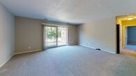 Located at 41 Briarwood Lane in Marlborough, MA, this single-floor unit offers a functional and well-organized layout. The living area is spacious, featuring plush carpeting, neutral gray-toned walls, a textured ceiling, and a sliding glass door that opens to an outdoor space, allowing natural light and views of surrounding greenery to fill the room. A pass-through window connects the living area to the kitchen, enhancing the open feel between spaces. A chandelier adds a subtle decorative touch to the adjoining dining area.

The kitchen is thoughtfully updated with white shaker-style cabinetry, marble-look countertops, a stainless steel sink with a modern pull-down faucet, a stainless steel electric range with an overhead exhaust hood, and a dishwasher. Wood-look flooring grounds the space with warmth and durability.

The bedrooms are carpeted and finished in neutral tones. One bedroom benefits from dual windows that bring in ample natural light, while another features a spacious closet with bifold doors and an additional window. The full bathroom includes a tub-shower combination, a white vanity with storage, a toilet, and wood-look flooring, all finished in a clean, bright white palette.