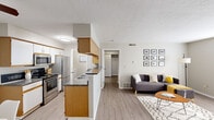 Located at 3100 Old Providence Ln in Columbus, Ohio, this one-bedroom, one-bathroom residence offers a thoughtfully designed layout that maximizes every inch of its single-floor footprint. The open-concept living and kitchen area serves as the heart of the home, where light-toned laminate flooring flows seamlessly throughout. The kitchen features warm oak cabinetry paired with white lower cabinets, dark granite-style countertops, stainless steel appliances including a range, microwave, and refrigerator, and a peninsula with a built-in sink that doubles as a breakfast bar. A ceiling fan and direct sightlines to the dining area make this space both functional and inviting. The living room is bright and open, benefiting from a large window that brings in natural light, and offers ample space for comfortable seating arrangements. A hallway connects the main living area to the private bedroom, which features plush carpet, a natural-light window, and access to a dedicated closet. The bathroom is clean and functional, complete with a tub-shower combination and a vanity with light countertops. Neutral gray tones and textured ceilings are consistent throughout, giving the home a cohesive and understated aesthetic.