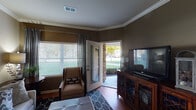 This single-floor residence is thoughtfully designed with warm earth tones and quality finishes that create a cohesive, inviting atmosphere throughout. The living area serves as a welcoming focal point, featuring rich hardwood flooring, crown molding, and large windows dressed with layered blinds and drape panels that allow abundant natural light. A glass door opens directly to an outdoor patio, providing easy access to exterior greenery and views of the surrounding landscape.

The kitchen is well-equipped, showcasing rich cherry wood cabinetry extending to the ceiling, granite countertops, and a full suite of stainless steel appliances including a range, over-the-range microwave, and refrigerator. Light hardwood flooring and recessed lighting complete the functional yet polished space.

The bedrooms offer a calm retreat, each featuring plush carpeting, ceiling fans, and generous windows with blinds and patterned drape panels. Warm taupe walls provide a neutral backdrop throughout.

The bathrooms are finished with granite-topped vanities set into rich wood cabinetry, large mirrors, and tub-shower combinations with curtain enclosures. Hardwood flooring extends into the bathrooms, maintaining a consistent, refined character across the entire residence.