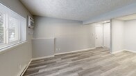 Located at 2141 Aurelius Rd in Holt, Michigan, this one-bedroom, one-bathroom unit offers a practical and well-organized single-floor layout. The combined living and dining area serves as the heart of the space, featuring light gray laminate wood flooring, soft neutral-toned walls, and a textured ceiling throughout. A window along the exterior wall allows natural light to filter in, while a wall-mounted air conditioning unit and baseboard heating provide year-round climate control. A half-wall partition adds a subtle architectural detail, defining the living area without enclosing it. The kitchen is equipped with a white electric range and ample cabinetry, positioned conveniently adjacent to the main living space. The bedroom offers a comfortable footprint with its own dedicated closet, a window with outdoor views, laminate flooring, and consistent neutral finishes that match the rest of the unit. Two additional closets throughout the unit provide generous storage capacity. The bathroom features a white vanity with a lighted medicine cabinet mirror, a full tub-shower combination, and coordinating light gray flooring. An entrance and hallway complete the layout, offering a smooth and functional flow between all areas of the home.