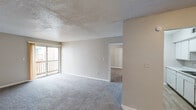 Located at 850 Lindbergh Dr in Jackson, Mississippi, this single-floor unit offers a straightforward and functional layout across several well-defined areas. The living room is a generously sized, carpeted space featuring a textured ceiling and a sliding glass door that opens to a private balcony, allowing for natural light and outdoor access. Adjacent to the living area is a dining space with light wood-style flooring, which connects seamlessly to the galley-style kitchen. The kitchen is efficiently designed with white cabinetry lining both walls, light countertops, a stainless steel sink, a coil-burner electric range, and a full-size refrigerator, all set on wood-look flooring. The bedroom is a spacious, carpeted room featuring a window for natural light, a textured ceiling, and a door providing direct access to the bathroom. The bathroom is equipped with a white vanity and sink topped by a lighted mirror, a toilet, and a full tub-shower combination with a clean white surround, complemented by wood-look tile flooring. Throughout the unit, neutral wall tones and white trim provide a clean, cohesive aesthetic. The layout, as visible from the overhead dollhouse view, is compact yet practical, making efficient use of available space.