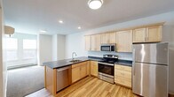 Located on the third floor at 10 Manseau St in Winooski, Vermont, this one-bedroom, one-bathroom unit offers a thoughtfully designed layout that maximizes its compact footprint. Light wood-tone flooring runs through the entryway and kitchen area, creating a warm and cohesive aesthetic from the moment you step inside. The entry hallway provides a clean transition into the main living space, with recessed lighting overhead and a wall-mounted rack for added convenience.

The kitchen is a functional highlight, featuring light maple cabinetry that extends to the ceiling for generous storage, dark countertops, and a full suite of stainless steel appliances including a refrigerator, electric range, built-in microwave, and dishwasher. The L-shaped peninsula layout adds prep space and openness to the room.

The bedroom is a comfortable, carpeted retreat with neutral tones and a large double-door closet offering ample storage. A window allows natural light to fill the room, complemented by a baseboard heating unit. The bathroom is clean and straightforward, featuring a full bathtub and shower combination with chrome fixtures. Throughout the unit, the design is clean, modern, and move-in ready.