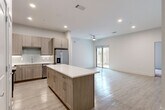 This well-designed single-floor residence offers 2 bedrooms, 3 bathrooms, and a thoughtful layout that maximizes both comfort and functionality. The open-concept kitchen and living area serves as the heart of the home, featuring light wood-tone cabinetry, a subway tile backsplash, stainless steel appliances including a French door refrigerator and built-in microwave, and a central island with a crisp white countertop — ideal for dining or meal prep. Recessed lighting and a ceiling fan keep the space bright and comfortable, while sliding glass doors in the living area open to an outdoor patio, filling the room with natural light. Light wood-tone flooring flows throughout the main living areas, complementing the neutral color palette. The bedrooms are carpeted and generously sized, with the primary bedroom offering ample space and access to a well-appointed closet featuring built-in shelving and hanging rods. The three bathrooms are finished with modern wood-tone vanities, white countertops, and large framed mirrors. One bathroom includes a full tub-shower combo with large-format tile surround. A dedicated laundry area and two closets add practical storage throughout. The overall aesthetic is clean, contemporary, and move-in ready.
