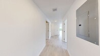 Located at 1080 NE 215th St in Miami, FL, this thoughtfully designed 2-bedroom, 2-bathroom residence offers a clean, modern aesthetic across a well-appointed single-floor layout. Light wood-look flooring flows throughout, complementing crisp white walls and an abundance of natural light.

The open-concept kitchen and living area serves as the heart of the home. The kitchen features two-tone cabinetry — warm wood lower cabinets paired with white upper cabinets — alongside light quartz countertops and a full suite of stainless steel appliances, including a refrigerator, electric range, microwave, and dishwasher. Track lighting above enhances the bright, airy atmosphere.

Both bedrooms are generously sized, with the primary bedroom offering direct access to a private balcony through a floor-to-ceiling sliding glass door, framing sweeping views of Miami's lush tree canopy. Large black-framed windows in both bedrooms invite natural light and outdoor scenery.

Each bathroom is finished with striking deep-blue glazed tile surrounding the tub-shower combinations, warm wood vanities, and large-format neutral floor tiles — a stylish contrast to the otherwise minimal palette. Additional highlights include three closets, an in-unit laundry area, and a bright hallway connecting all rooms cohesively.