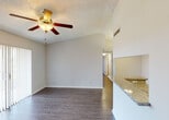 Located at 3505 W Atlantic Blvd in Pompano Beach, Florida, this single-floor unit offers a well-designed layout with consistent wood-look flooring throughout. The open living area is bright and airy, featuring a ceiling fan with light fixture and large sliding glass doors fitted with vertical blinds that allow natural light to fill the space. A pass-through window with a granite countertop connects the living area to the kitchen, creating an open and communicative flow between the two spaces. The kitchen is thoughtfully designed with dark espresso cabinetry, granite countertops, an undermount sink, and stainless steel appliances including a refrigerator, electric range, over-the-range microwave, and dishwasher. A tray ceiling with flush-mount lighting adds a polished touch to the kitchen area. The bedrooms are comfortably sized, each equipped with ceiling fans and ample natural light from windows with vertical blinds. The bathroom features a granite-topped dark vanity, a tub-shower combination, and wood-look flooring that carries throughout. Neutral tones and clean white walls create a bright, versatile canvas across all rooms, while textured ceilings add a classic residential character to the overall space.