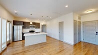 Located on Central Avenue in Indianapolis, this thoughtfully designed one-bedroom, one-bathroom residence offers a clean, contemporary aesthetic across its well-planned single floor. Light hardwood flooring flows consistently throughout every room, lending warmth and cohesion to the space.

The open-concept kitchen and living area serves as the heart of the home. The kitchen is outfitted with stainless steel appliances — including a refrigerator, electric range, and microwave — complemented by rich, dark wood cabinetry and crisp white quartz countertops. A spacious center island with an integrated sink and pendant globe lighting above creates an ideal space for both cooking and entertaining. A private balcony is accessible directly from the kitchen and living area, offering views of the surrounding neighborhood.

The living area is generously proportioned, bathed in natural light from large floor-to-ceiling windows fitted with horizontal blinds. A ceiling fan provides comfort overhead.

The bedroom is a well-sized retreat featuring two windows with neighborhood views, a ceiling fan, and direct access to a dedicated closet with built-in shelving. The full bathroom includes a dark wood vanity with white quartz countertop, a mirrored medicine cabinet, and a tiled tub-shower combination. In-unit laundry is also present, adding everyday convenience to this polished, modern residence.