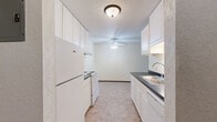 Located at 521 Westview Dr in Hastings, MN, this one-bedroom, one-bathroom residence offers a practical and well-organized single-floor layout. The galley-style kitchen features white cabinetry extending to the ceiling for ample storage, dark countertops, a double stainless steel sink, and standard appliances including a refrigerator and electric range. A ceiling fan with light fixture and tile flooring complete the kitchen's clean, functional design.

The living area is comfortably sized with neutral carpet, a ceiling fan, a wall-mounted air conditioning unit, and a baseboard heater along the exterior wall. A large window with vertical blinds allows natural light to fill the space and provides outdoor views of the surrounding greenery.

The bedroom is a generously proportioned room with soft carpet, its own baseboard heater, a window with vertical blinds for natural light, and a textured ceiling. A ceiling fan provides additional climate comfort in this restful retreat.

The full bathroom includes a white tiled tub and shower combination, accented with chrome accessories such as grab bars, shelving caddies, and towel bars, presenting a clean and well-maintained space.

A connecting hallway ties the layout together, offering efficient flow between all areas of the home. Baseboard heating is consistent throughout, ensuring year-round comfort in this straightforward and livable Hastings residence.