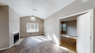 Located at 2053 NE 106th Ave in Hillsboro, Oregon, this single-floor home offers a thoughtfully designed layout filled with natural light throughout. The open living area is a standout, featuring soaring vaulted ceilings, a tile-surround fireplace, and durable hardwood-style flooring that extends across the main living spaces. Abundant windows dressed with blinds invite generous sunlight, while a ceiling fan adds to the room's comfort. An arched doorway connects the living area to the kitchen, which is equipped with rich dark wood cabinetry, warm laminate countertops, a stainless steel sink, and matching stainless appliances including a range, microwave, and refrigerator. A secondary carpeted living or dining area features a glass door leading to the outdoors, offering views of the surrounding greenery. The bedrooms are carpeted for comfort, each with ample natural light and closet space, including a mirrored sliding-door closet in one room. The primary bathroom features a dual-sink vanity with a wide countertop, dark wood cabinetry, hardwood-style flooring, and a tub-shower combination. A second full bathroom mirrors the same finishes with a single-sink vanity and tub-shower. Neutral taupe walls and textured ceilings carry throughout, creating a cohesive and welcoming ambiance.