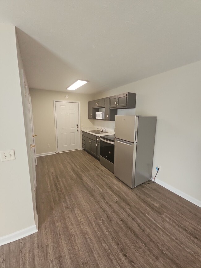 Bright studio kitchen featuring shaker style cabinetry, laminate countertops, and a compact layout - 1351 N Dixie Ave