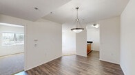 Located at 20227 Saticoy St in the Winnetka neighborhood of Los Angeles, this single-floor, 2-bedroom, 1-bathroom unit offers a functional and comfortable layout. The open-concept living and dining area features rich wood-style vinyl flooring and a stylish pendant light fixture, creating a welcoming central gathering space. The kitchen is equipped with warm honey-toned cabinetry, dark granite countertops extending to a breakfast bar, a gas range, and overhead microwave — all designed for efficient use of space. Both bedrooms are finished with plush wall-to-wall carpeting and feature large windows dressed with vertical blinds that invite generous natural light and outdoor views of the surrounding neighborhood. Each bedroom includes a sliding-door closet for ample storage. The full bathroom is finished with dark wood-style flooring, a tile-surround soaking tub and shower combination, and a vanity with dark countertop. Throughout the unit, the clean white walls and bright, airy atmosphere lend a neutral, move-in-ready appeal. The living room opens to additional windows and a sliding glass door, further enhancing the sense of openness and connectivity to the outside.