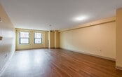 This single-floor unit offers a clean, functional layout designed with both comfort and accessibility in mind. The expansive living area is finished with rich hardwood flooring that extends throughout the main spaces, complemented by warm yellow-toned walls and crisp white trim that lend a bright, welcoming ambiance. Natural light filters in through green-framed windows, adding character to the open interior.

The kitchen is thoughtfully designed with a U-shaped layout, featuring white cabinetry with ample storage, dark laminate countertops, recessed lighting, and white appliances including a wall oven, cooktop, and refrigerator. Light tile flooring ties the space together seamlessly.

The bedroom area is generously sized, offering a double-door closet and direct access to a well-appointed bathroom. The bathrooms are designed with accessibility in mind — one features a roll-in shower with grab bars and a vanity with a mirror, while the other includes a combination tub and shower unit, also equipped with a grab bar for added safety. Both bathrooms are finished with light tile flooring and soft neutral tones.

A pass-through window connects the kitchen to the living area, enhancing the open feel of the floor plan. Overall, this space delivers a practical yet comfortable environment with thoughtful design details throughout.