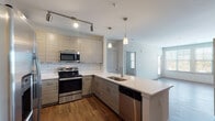 This well-designed single-floor residence at 3000 Dominion Ridge Way in Morrisville, NC offers a thoughtfully planned layout with modern finishes throughout. The contemporary kitchen is a standout feature, showcasing textured flat-panel cabinetry, a classic subway tile backsplash, gleaming white quartz countertops, and a full suite of stainless steel appliances including a French door refrigerator, electric range with microwave, and dishwasher. A peninsula with an undermount sink and pendant lighting makes the kitchen both functional and stylish, while track lighting adds further illumination. Rich hardwood-style flooring flows through the main living areas and entryway, creating a warm and cohesive aesthetic. The open living space is bathed in natural light from large windows and offers access to a private balcony, extending the living area outdoors. Bedrooms are finished with plush carpeting, ceiling fans, and ample natural light from well-placed windows. The primary bathroom features a glass-enclosed shower, soaking tub, dual-sink vanity with modern cabinetry, and direct access to a spacious walk-in closet with built-in shelving. An in-unit laundry area adds everyday convenience. Neutral tones and clean lines throughout lend the space a fresh, modern ambiance.