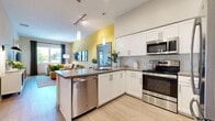 Located at 770 S Harbor Blvd in Fullerton, CA, this well-designed one-bedroom, one-bathroom residence offers a thoughtfully laid-out floor plan with a seamless flow between living spaces. The open-concept kitchen and living area serves as the heart of the home, featuring white shaker cabinetry, stainless steel appliances including a range, microwave, dishwasher, and refrigerator, and a peninsula with a dark countertop that doubles as a breakfast bar. Pendant lighting and track lighting illuminate the space, while light wood-style flooring extends throughout the main living areas. A warm yellow accent wall adds a vibrant pop of color, connecting the kitchen to a cozy dining nook with a large mirror that enhances the sense of space. The living room is bright and inviting, with a large window that brings in natural light and views of the surrounding greenery. The bedroom features plush carpeting, a generous window with outdoor views, and access to a dedicated closet. The bathroom is finished with light tile flooring, white cabinetry, a dark countertop vanity, and a lighted mirror, offering a clean and modern aesthetic. A hallway connects all areas efficiently, completing this polished and comfortable Fullerton residence.