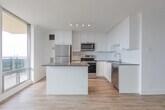 Located at 7 Jackes Ave in Toronto's sought-after Midtown neighbourhood, this well-appointed 2-bedroom, 2-bathroom residence offers a bright and modern living experience across a thoughtfully designed single floor. Light-toned hardwood-style flooring flows throughout, complementing the clean white walls and creating a cohesive, airy atmosphere.

The open-concept kitchen and living area serves as the heart of the home. The kitchen is outfitted with white shaker-style cabinetry extending to the ceiling, a classic white subway tile backsplash, stainless steel appliances including a full-size refrigerator, range, and over-the-range microwave, and a generous island with a dark stone countertop. The adjacent living room is bathed in natural light through expansive floor-to-ceiling sliding glass doors that frame impressive views of the Toronto skyline.

The spacious primary bedroom also benefits from large sliding glass doors with sweeping city views. Both bathrooms are finished in a clean, contemporary style — one featuring a tiled tub-shower combination with white subway tiles and chrome fixtures, and the other with a wide vanity and large mirror. A dedicated in-unit laundry area and two hallways add to the functional layout of this well-designed urban residence.