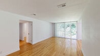 Located at 2700 Brigadoon Drive in Raleigh, NC, this single-story, 3-bedroom, 1-bathroom home offers a well-organized layout with consistent hardwood flooring running throughout. The living room is a standout space, bathed in natural light from a large sliding glass door fitted with vertical blinds that open to lush, tree-lined outdoor views. A ceiling fan and an additional window in the adjacent area further brighten this open living space.

The kitchen features white cabinetry, light marble-style countertops, a stainless steel sink, and earthy stone tile flooring, providing a functional and clean workspace. Each of the three bedrooms is finished with the same warm hardwood floors. The primary bedroom includes a spacious sliding-door closet and vertical shiplap-style wall paneling as a design accent. A secondary bedroom also features shiplap wall detailing and a natural light window, while the third bedroom includes its own closet access.

The bathroom is clean and well-appointed with a white vanity, dark granite countertop, wood-look tile flooring, a tub-shower combination, and a safety grab bar. Two hallways connect the rooms efficiently throughout the home. The overall ambiance is bright, clean, and move-in ready, with a neutral palette that complements the natural warmth of the hardwood floors.