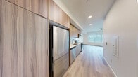 Located at 18807 8th Ave NE in Shoreline, Washington, this modern studio offers a well-designed, open-concept layout that efficiently combines the kitchen and living area into a single, cohesive space. Light hardwood flooring runs throughout, enhancing the bright, airy atmosphere created by large windows that invite generous natural light.

The kitchen is thoughtfully appointed with a full suite of stainless steel appliances, including an LG refrigerator, Whirlpool dishwasher, electric range, and built-in microwave. Warm wood upper cabinetry contrasts elegantly with the light gray lower cabinets, while a light blue tile backsplash and white quartz countertops add a polished, contemporary touch. Floor-to-ceiling cabinetry along one wall provides ample storage.

The living area is an open, sun-filled space with crisp white walls, a ceiling fan with integrated lighting, and a wide window framing views of the surrounding neighborhood. A sliding panel door offers a clean, modern way to define zones within the layout.

The bathroom continues the minimalist aesthetic with matching light hardwood floors, a gray vanity with a white countertop and mirror, brushed nickel hardware, and a clean, functional design. Overall, this space presents a cohesive, modern interior suited for efficient, contemporary living in Shoreline.