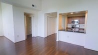 Located at 3514 Lancaster Ave in the University City neighborhood of Philadelphia, PA, this single-floor residence offers a well-designed, open-concept layout that balances modern finishes with functional living. Rich, dark hardwood flooring runs throughout the main living area, lending warmth and a sense of continuity to the space. Soaring ceilings enhance the airy, spacious atmosphere, making the living area feel expansive and bright. The kitchen is positioned on one side of the open floor plan and features a peninsula with a dark stone countertop, warm wood cabinetry, and stainless steel appliances including a built-in microwave and range. This setup makes the kitchen both practical and visually appealing, ideal for cooking and entertaining. The layout also includes closet space and connecting hallways that lead to additional areas of the unit, providing ample storage and privacy. The clean white walls and neutral color palette throughout create a versatile backdrop that adapts well to a variety of interior styles. Overall, the space presents a contemporary and well-appointed environment in a prime Philadelphia location.