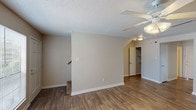 This two-story residence offers a well-organized layout spanning two levels. The main floor features a welcoming entryway with wood-look plank flooring that extends through the living areas and kitchen. The kitchen is efficiently designed with white cabinetry, light countertops, a stainless steel sink, a dishwasher, and a full suite of white appliances including an electric range and refrigerator. A window above the sink brings in natural light. The main level also includes a convenient half bathroom with a vanity and mirror. Upstairs, the two bedrooms are carpeted for comfort and each includes a ceiling fan with light fixture. Both bedrooms offer closet storage, with the primary bedroom featuring a walk-in closet. The full bathroom on the upper level is outfitted with a tub/shower combination and chrome fixtures. Throughout the home, neutral warm-toned walls, textured ceilings, and consistent trim details create a clean, cohesive aesthetic. A staircase connects the two floors, reinforcing the functional, multi-level design of this residence.