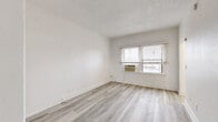 Located at 1310 S Wilton Place in the heart of Los Angeles, CA, this one-bedroom, one-bathroom unit offers a clean, modern aesthetic throughout. Light wood-style vinyl flooring runs seamlessly across the entire space, complementing the crisp white walls and creating a bright, cohesive feel.

The spacious bedroom is a standout feature, offering generous room for furnishings, a mirrored sliding-door closet that enhances the sense of space, and a window-mounted air conditioning unit for personalized climate control. Natural light filters in through windows fitted with white horizontal blinds.

The kitchen is thoughtfully designed with sleek white cabinetry extending to the upper walls, a dark countertop, an undermount sink with a matte black faucet, and a window that brings in additional natural light — ideal for both cooking and casual dining.

The bathroom presents a clean, minimalist look with a white vanity, a black-framed mirror, matte black hardware accents, a full soaking tub with shower, and matching light flooring that ties the space together.

Throughout the unit, hallways connect the rooms efficiently, and three closets provide exceptional storage options rarely found in similarly sized spaces. The textured ceiling adds a subtle architectural detail, while the overall bright, neutral palette makes this a move-in-ready home in a well-connected Los Angeles neighborhood.