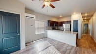 Located at 1017 Tyre Heights in Colorado Springs, Colorado, this single-story unit offers a thoughtfully designed layout that balances functionality with modern aesthetics. The open-concept living and kitchen area serves as the heart of the home, where wood-look plank flooring, neutral walls, and natural light filtering through horizontal blinds create a clean, inviting atmosphere. A ceiling fan overhead adds both comfort and character to the shared space.

The kitchen is well-appointed with rich dark-toned cabinetry, granite-style countertops, a tile backsplash, and a full suite of stainless steel appliances including a refrigerator, electric range, and microwave. A peninsula with an integrated sink provides additional prep space and casual seating opportunities. A wall-mounted mini-split unit ensures efficient climate control throughout the living area.

The bedrooms are carpeted for comfort, with multiple windows allowing generous natural light. One bedroom features its own ceiling fan and wall-mounted mini-split, along with direct access to a bathroom. The bathroom includes a granite-topped vanity with dark cabinetry, a tub-shower combination, and wood-look flooring, maintaining a cohesive design throughout. The overall aesthetic is contemporary, clean, and move-in ready.