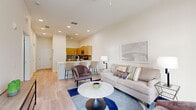 Located on International Drive in Orlando, FL, this thoughtfully designed 1-bedroom, 1-bathroom residence offers a seamless blend of modern aesthetics and functional living. The open-concept layout connects the kitchen, dining, and living areas into a cohesive, light-filled space. Light wood-style flooring flows throughout, complementing the neutral palette that defines the interior.

The kitchen is equipped with natural wood cabinetry, white quartz countertops, stainless steel appliances, and a gray tile backsplash. A peninsula with bar seating provides a casual dining option that transitions naturally into the living area. The living room features large floor-to-ceiling windows that frame views of palm trees and lush outdoor greenery, filling the space with natural light. A ceiling fan adds comfort to the airy setting.

A bright hallway leads to the well-proportioned bedroom, which features carpeted flooring, dual windows overlooking a landscaped outdoor area, and a closet. The adjacent full bathroom includes a wood-toned vanity with a white countertop and a tiled shower-tub combination. The overall ambiance is clean, contemporary, and inviting — an efficient yet stylish residence in the heart of Orlando.