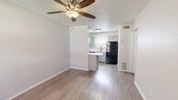 This 1-bedroom, 1-bathroom unit offers a thoughtfully arranged single-floor layout that maximizes every square foot of available space. The open-concept living room and kitchen area serves as the heart of the unit, featuring warm-toned laminate wood flooring, neutral gray walls, and a textured ceiling with a ceiling fan and light fixture. A large window floods the living area with natural light, creating an airy, welcoming atmosphere.

The kitchen is efficiently designed in a galley style, equipped with gray cabinetry, light speckled countertops, a stainless steel dishwasher, an electric range, and a black refrigerator. A window above the sink adds additional natural light to the cooking space. Adjacent to the kitchen is a dedicated pantry, providing extra storage convenience.

The bedroom is a comfortable, well-proportioned space finished with plush carpeting and neutral walls. A window with blinds allows for natural light and privacy control, while a dedicated closet offers practical storage. The transition from the living area into the bedroom is facilitated by a hallway.

The bathroom completes the unit's layout. Throughout, the consistent use of neutral tones, laminate flooring in common areas, and carpet in the bedroom creates a cohesive and functional living environment.