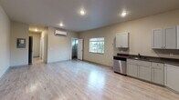 Located at 6019 Lake Grove St SW in Lakewood, Washington, this single-floor unit offers a clean, modern design throughout. The open-concept living and dining area is finished with light wood-style flooring and neutral warm-toned walls, creating a bright and welcoming atmosphere. A wall-mounted mini-split HVAC unit provides efficient climate control, and recessed lighting illuminates the space. A window overlooking the outdoors brings in natural light.

The kitchen is well-appointed with white shaker-style cabinetry, dark countertops, and a full suite of stainless steel appliances including a range, over-the-range microwave, refrigerator, and dishwasher. The layout maximizes storage and functionality with ample upper and lower cabinet space.

The bedroom features light wood-style flooring, neutral walls, and a sliding glass door with vertical blinds, allowing for additional natural light and outdoor access. A spacious closet with in-unit washer and dryer hookups adds practical convenience.

The bathroom is finished with large-format tile in the tub and shower surround, complemented by tile flooring, a vanity with a wide mirror, and a small privacy window that allows natural light into the space. Overall, the unit presents a fresh, move-in-ready environment with consistent modern finishes throughout.