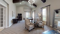 Located at 201 River Pointe Dr in Conroe, Texas, this single-floor clubhouse offers a well-appointed gathering space designed for both comfort and function. The interior is defined by dramatic vaulted ceilings with dark wood beam accents, creating a sense of openness and architectural distinction throughout.

The main lounge area features plush, tufted seating, patterned carpeting, and floor-to-ceiling draped windows that invite abundant natural light and views of the surrounding grounds. A large floor mirror and tasteful décor add to the refined ambiance of this welcoming space.

Adjacent to the lounge is a generously sized recreation room, complete with a billiards table, additional seating, a mounted flat-screen television, and a dining area — all beneath a striking chandelier that anchors the room with elegance.

The clubhouse includes two distinct kitchen areas. The primary kitchen is expansive, featuring rich dark cabinetry, granite countertops, a mosaic tile backsplash, stainless steel appliances including a range and dishwasher, and pendant lighting over a large island. A secondary kitchenette mirrors this design with matching cabinetry, granite surfaces, and a stainless steel sink — ideal for catering or event use.

Throughout the space, large-format tile flooring, recessed lighting, and neutral wall tones create a cohesive, upscale aesthetic suited for community gatherings and events.