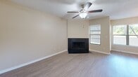 Located at 2690 Enterprise Rd E in Clearwater, FL, this 2-bedroom, 3-bathroom residence offers a well-organized single-floor layout designed for comfortable everyday living. The living room serves as a central gathering space, highlighted by a striking dark-surround fireplace, a ceiling fan, and a textured ceiling — all complemented by light wood-look flooring that flows throughout the main areas. Adjacent to the living room, the dining area features warm hardwood-style flooring and a modern pendant light fixture, with a window that invites natural light. The kitchen is thoughtfully updated with bold navy cabinetry, light countertops, a tray ceiling with recessed track lighting, and a full suite of stainless steel appliances, including a refrigerator, range, and built-in microwave. Both bedrooms are carpeted and include ceiling fans and closets, with the primary bedroom offering generous proportions and good natural light through slatted windows. The three bathrooms are clean and functional, featuring white tiled surrounds — one with a walk-in shower and another with a tub/shower combination — alongside white vanities and wood-look flooring. A wide hallway connects the spaces efficiently, adding to the home's open and airy feel throughout.